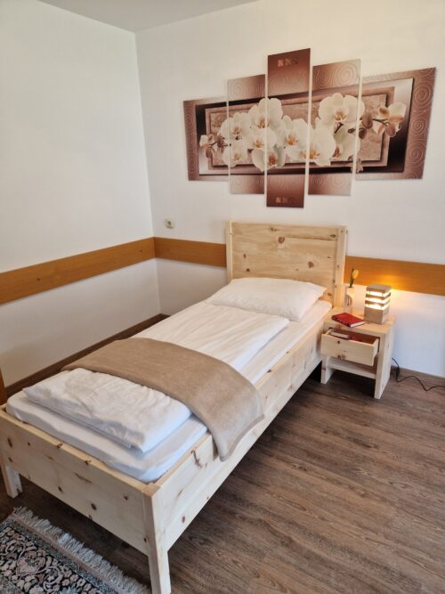 Zirbenbett 6 als Einzelbett in einem hellen Schlafzimmer