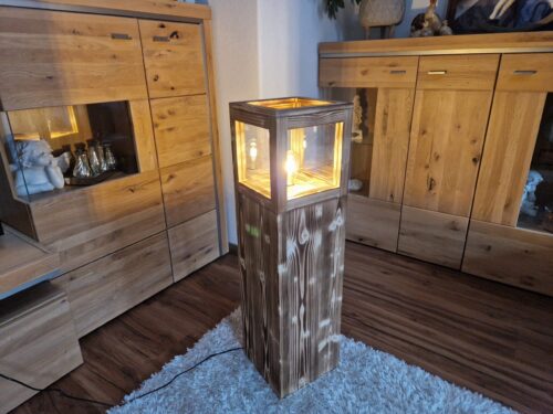 Stehlampe Flame aus Zirbenholz neben einer Kommode