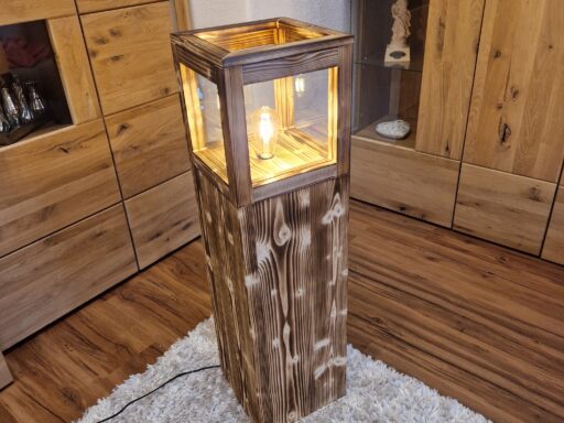 Stehlampe Flame aus Zirbenholz auf einem Teppich, beleuchtet