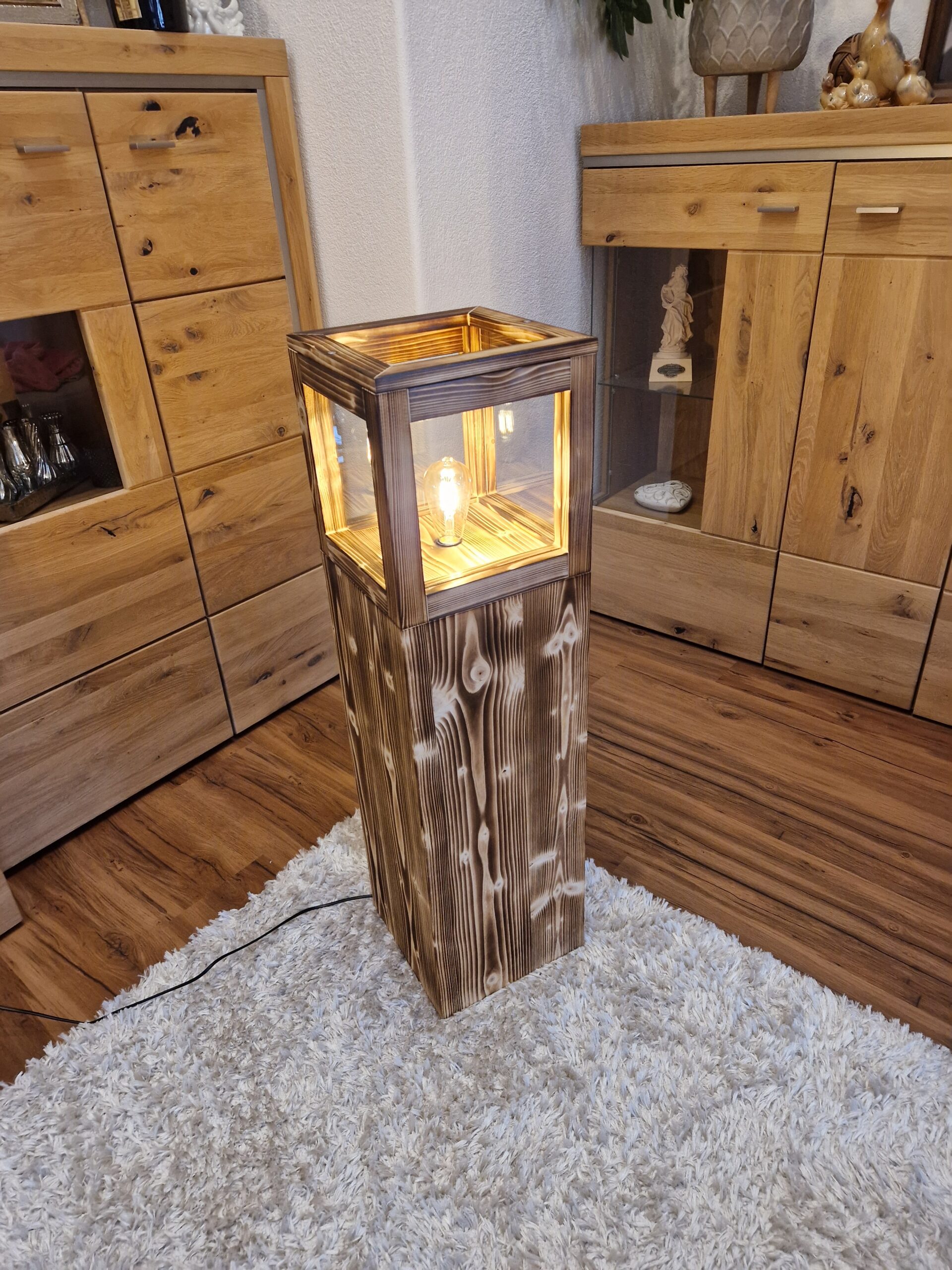 Stehlampe Flame aus Zirbenholz auf einem Teppich, beleuchtet