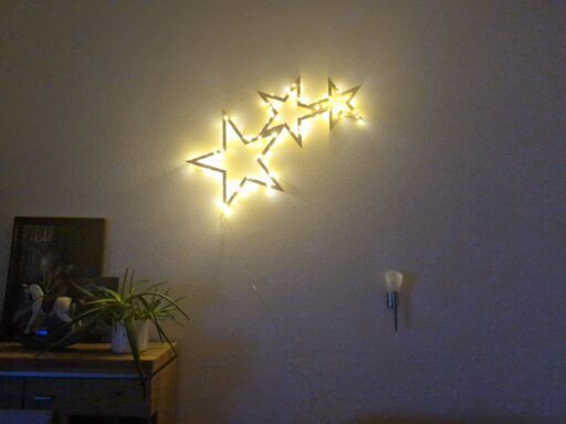Sternschnuppe aus Zirbenholz mit Lichterkette an einer Wohnzimmerwand