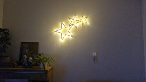 Sternschnuppe aus Zirbenholz mit Lichterkette an einer Wohnzimmerwand