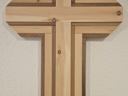 Wandkreuz aus Zirbenholz mit breiten Lattenbalken an heller Wand