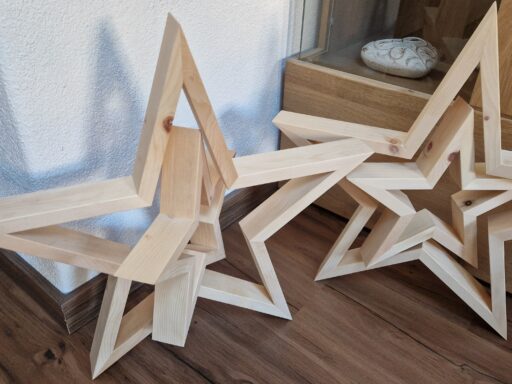 Weihnachtssterne aus Zirbenholz vor einer Kommode
