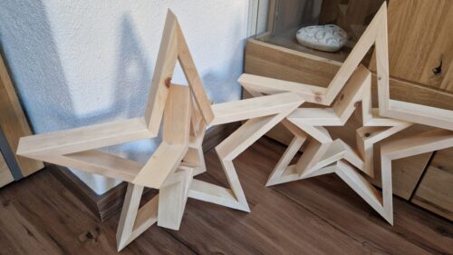 Weihnachtssterne aus Zirbenholz vor einer Kommode