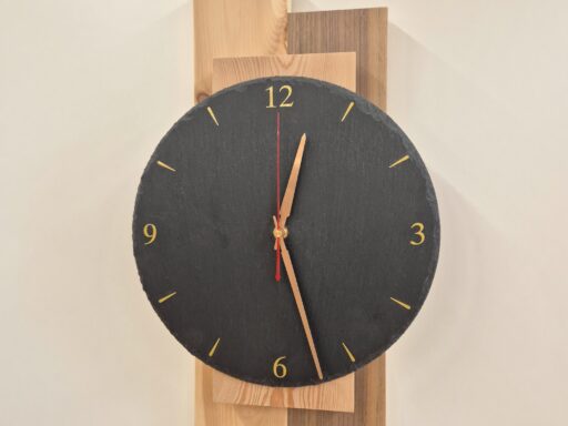 Wanduhr mit dunklem Zifferblatt auf Zirbenholz-Leisten