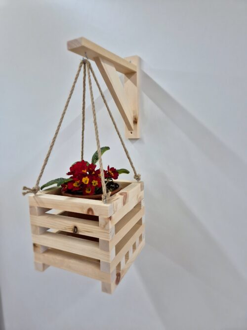 Blumenampel aus Zirbenholz an der Wandhalterung, bepflanzt mit roter Primel