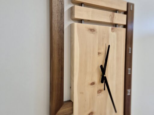 Wanduhr aus Zirbenholz mit dunklem Rahmen, schräge Ansicht