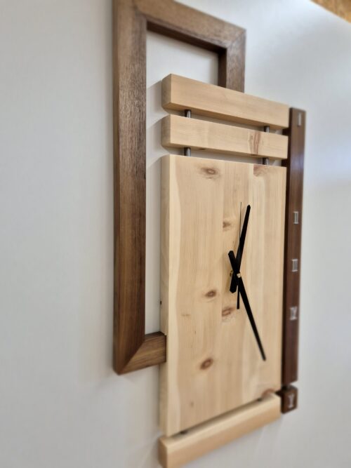Wanduhr aus Zirbenholz mit dunklem Rahmen, schräge Ansicht