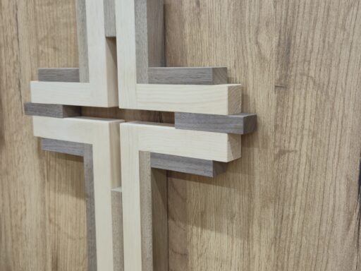 Wandkreuz aus Zirbenholz in Weiß und Natur an einer Holzwand