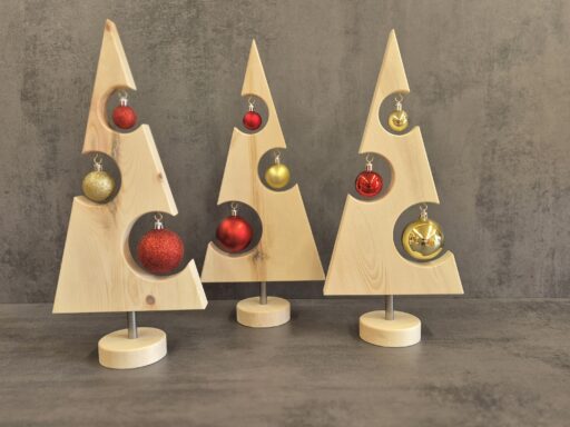 Drei Weihnachtsbäume aus Zirbenholz mit roten und goldenen Kugeln