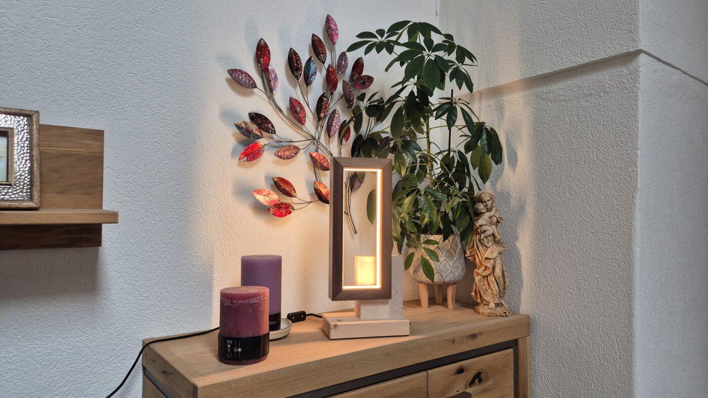 Tischlampe aus Zirbenholz, beleuchtet auf einer Kommode neben einem Wandbild