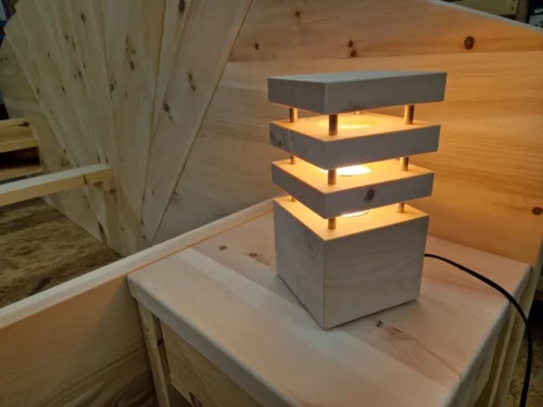 Beleuchtete Nachttischlampe aus Zirbenholz auf einem Nachtkästchen