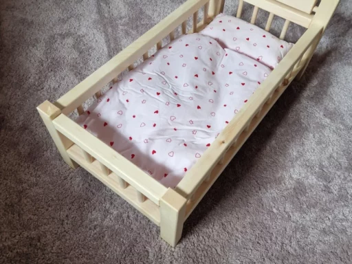 Puppenbett aus Zirbenholz mit bunter Bettwäsche