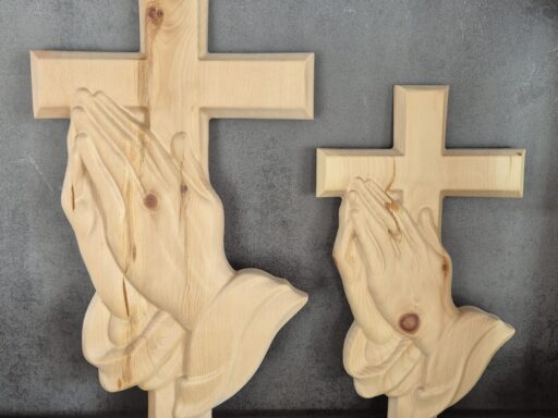Zwei Wandkreuze aus Zirbenholz mit betenden Händen in zwei Größen nebeneinander