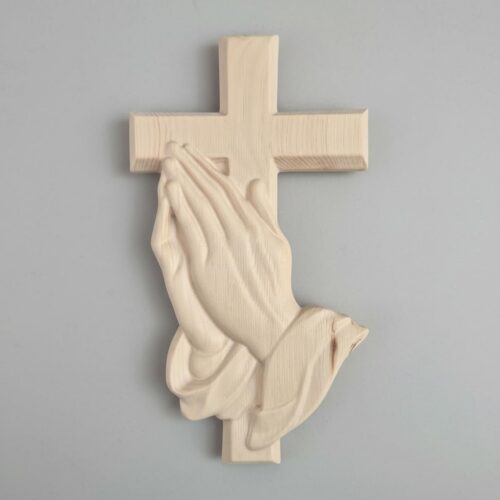 Wandkreuz aus Zirbenholz mit betenden Händen an heller Wand