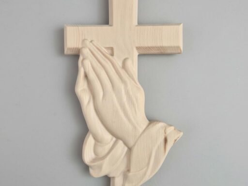 Wandkreuz aus Zirbenholz mit betenden Händen an heller Wand