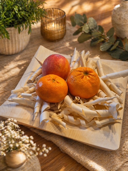 Zirbenschale mit Mandarinen auf einem gedeckten Tisch